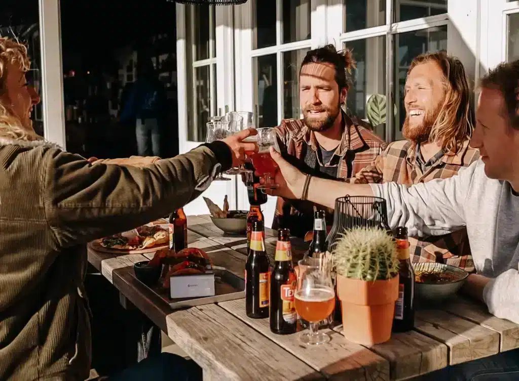 Jonge mannen bij strandtent proosten met Zandvoorts getijdenbier op een leuke dag aan het strand