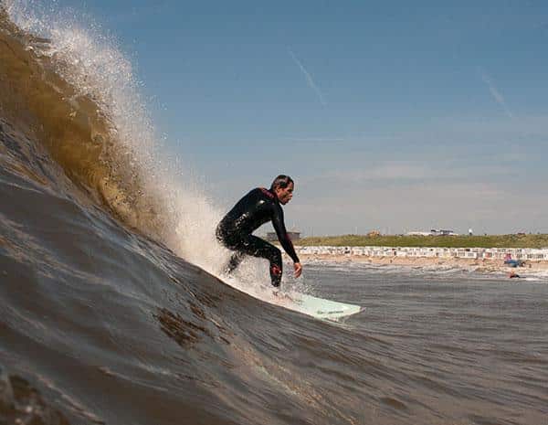 Surfer op zijn board die een golf pakt in de Noordzee voor Zandvoort