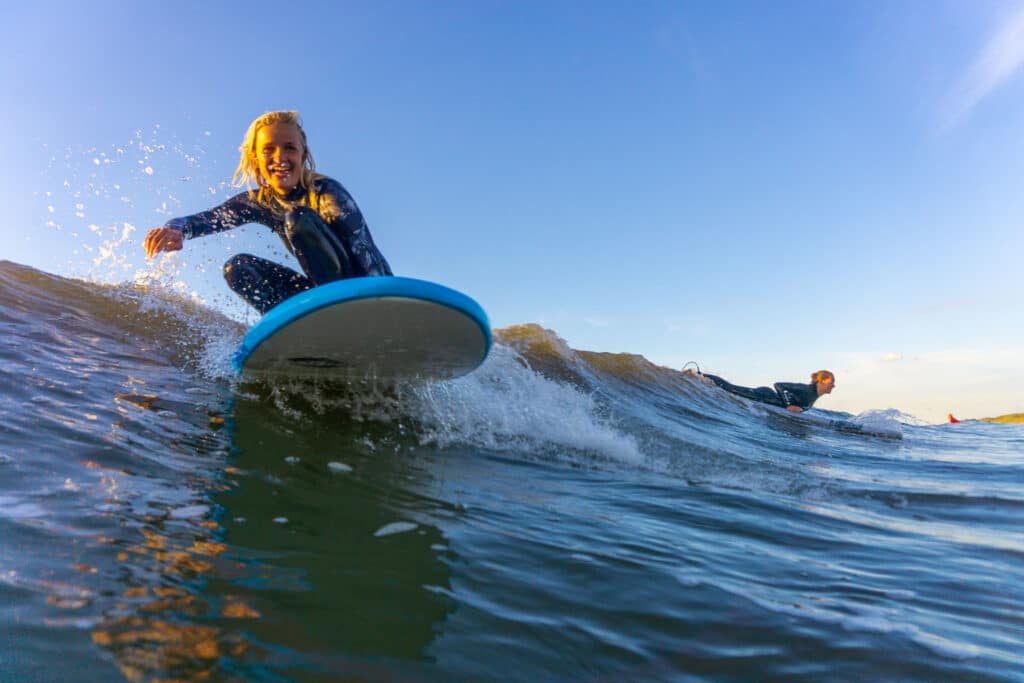 Vrouwelijke surfer op een surfboard kijkend in de camera terwijl ze een golf pakt