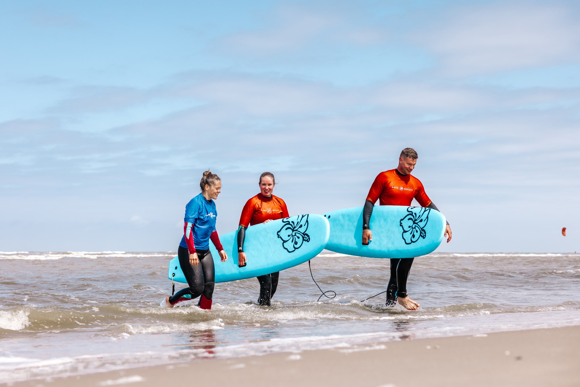 twee mensen lopen met instructeur uit de zee na hun golfsurfles