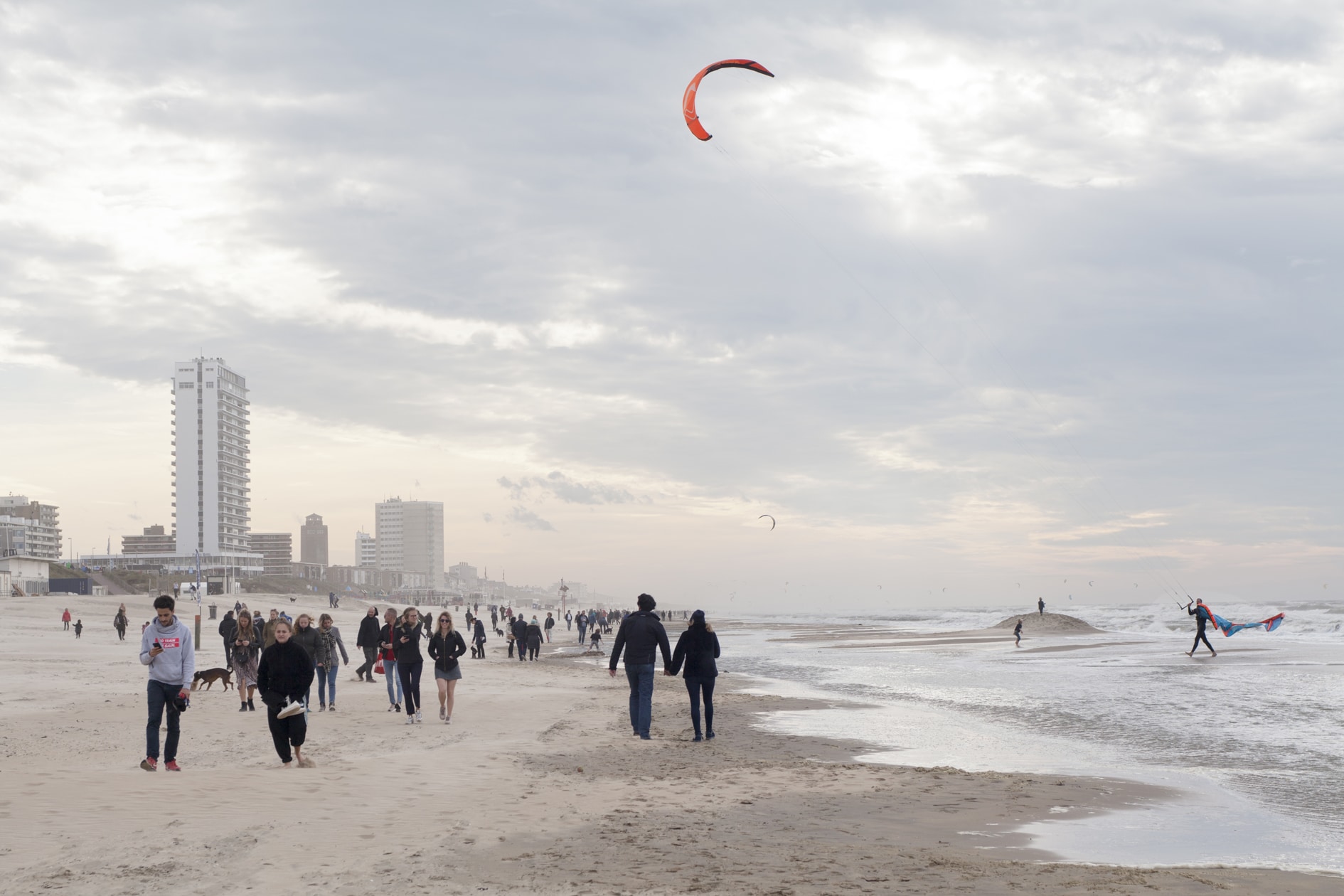 Wandelaars op het strand met een kiter in zee