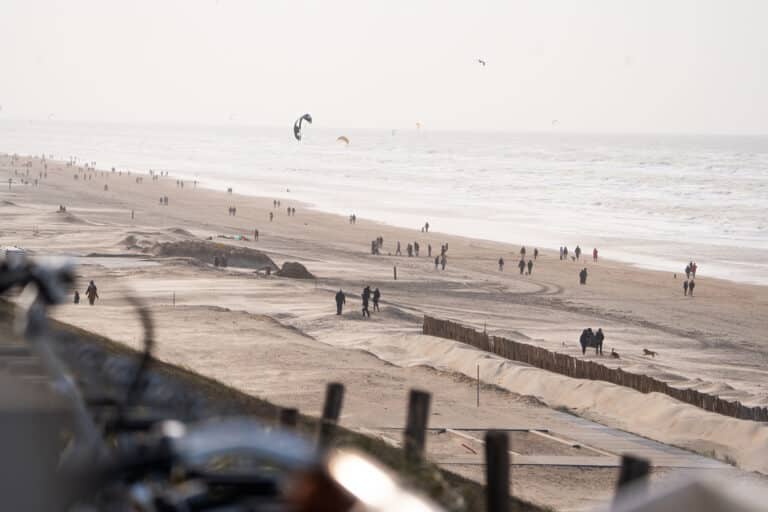 Overzichtsfoto van het Zandvoortse strand in de winter met in de verte wandelaars en kitesurfers