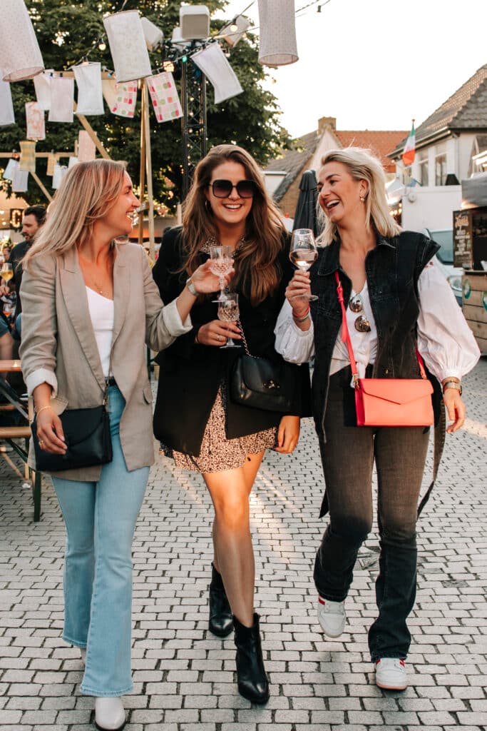 Drie meiden lopen lachend met een drankje tijdens het evenement Wereldse Smaken.