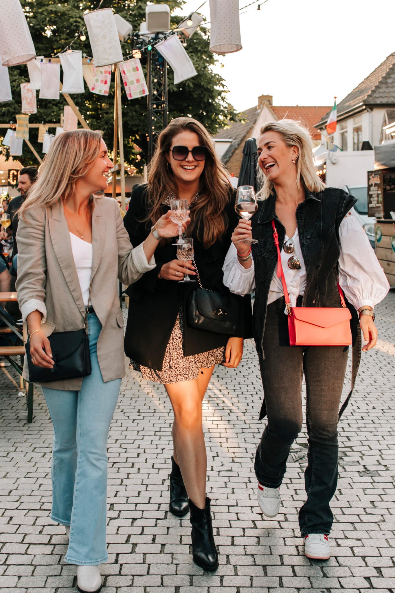 Drie meiden lopen lachend met een drankje tijdens het evenement Wereldse Smaken.