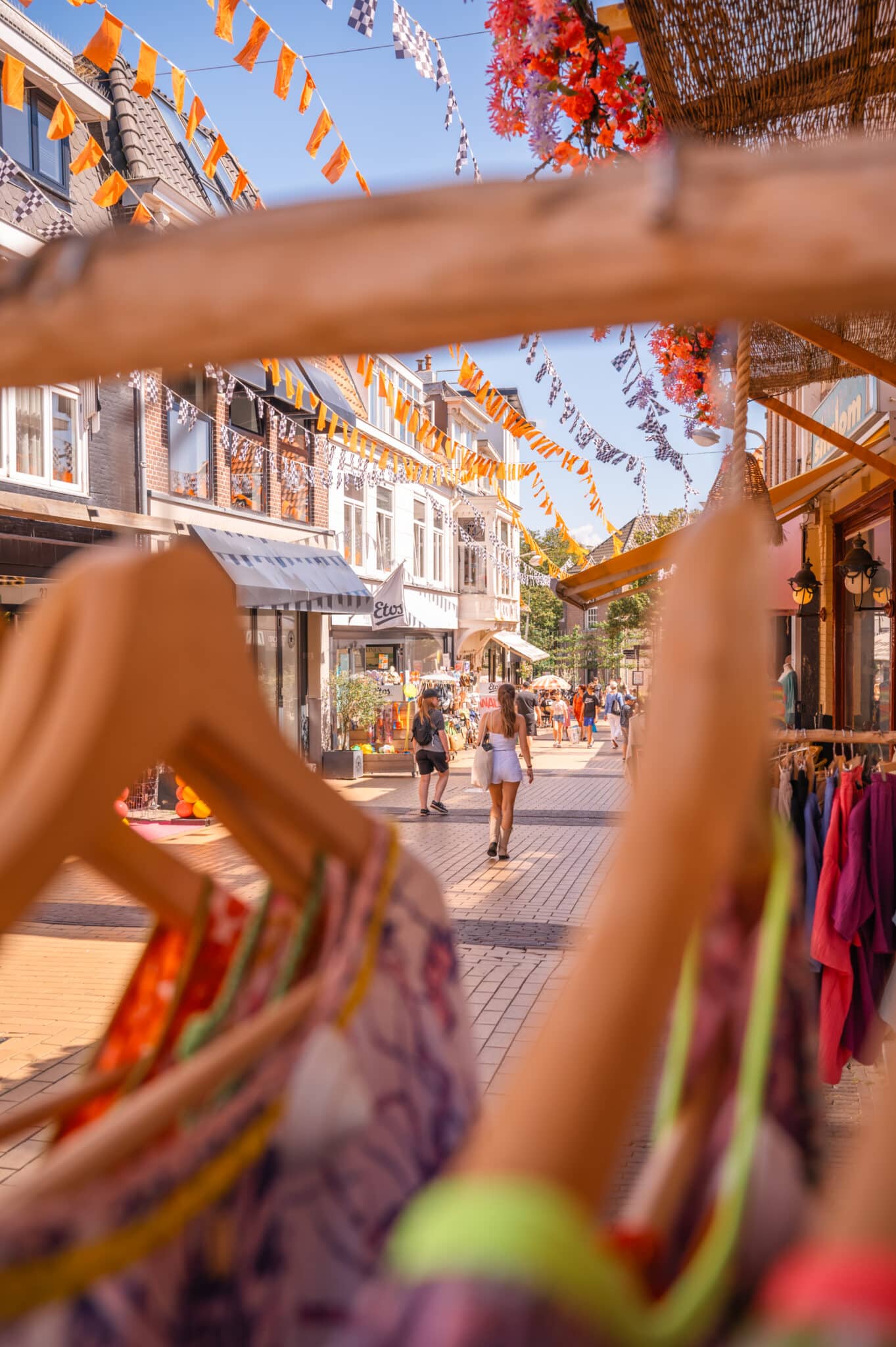 Een doorkijkje vanaf de Kerkstraat, kijkend naar beneden naar de aflopende winkelstraat, versierd met vrolijke vlaggetjes in de zomer.