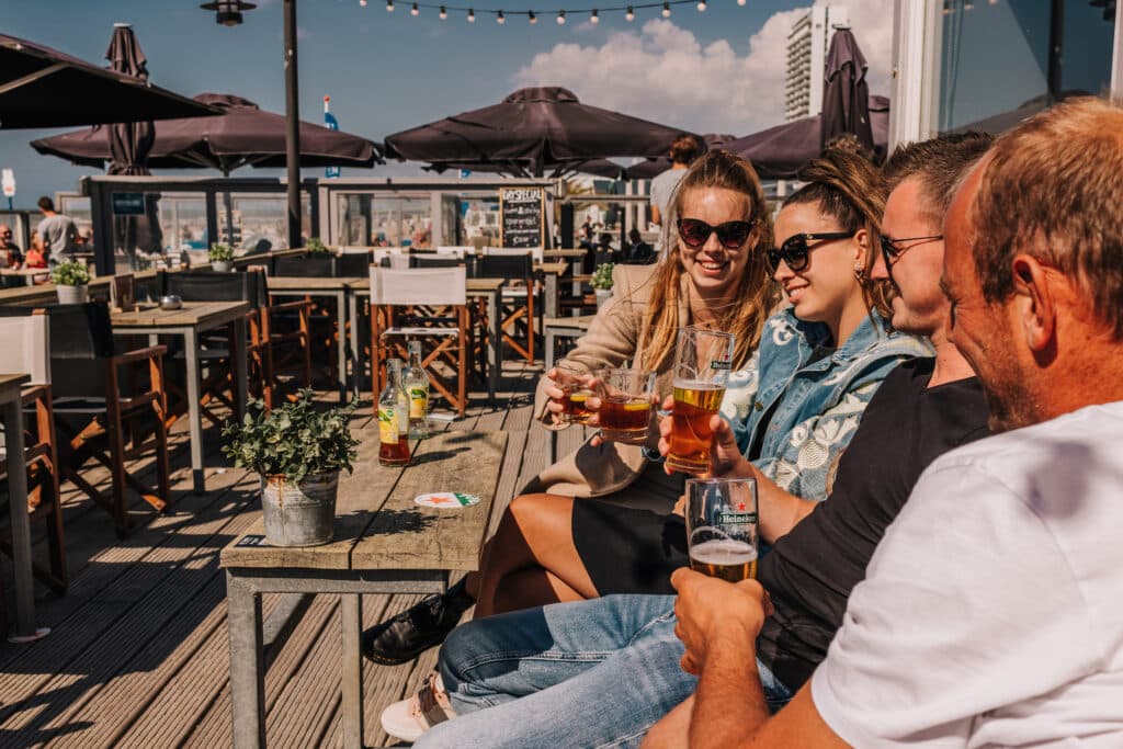 Groep vrienden drinkt een drankje bij strandpaviljoen De Haven van Zandvoort.