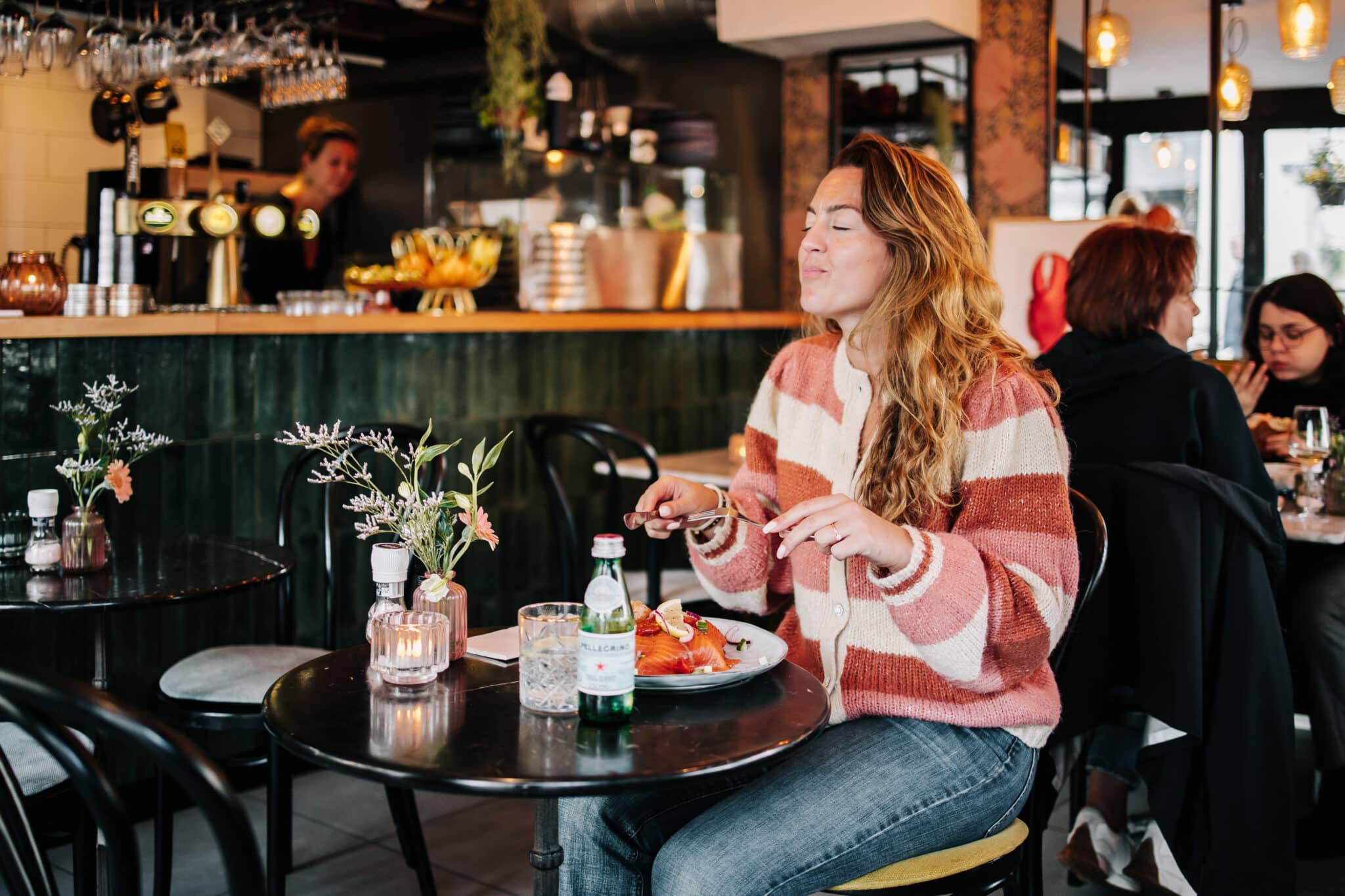 Vrouw geniet in het dorp van een broodje bij restaurant Le Bar.