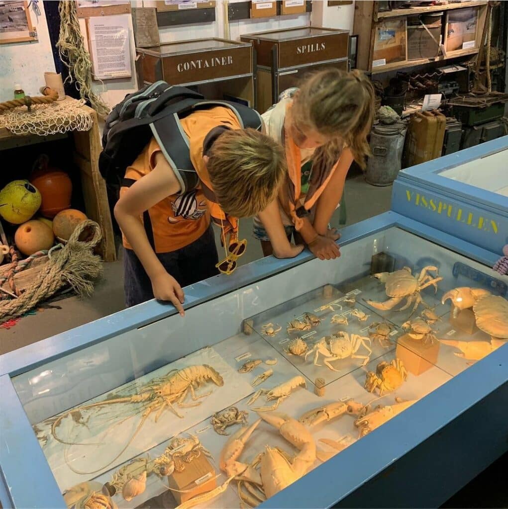 Twee kinderen buigen zich over een vitrine met gejutte spullen in het Zandvoortse Jutters Muzeeum