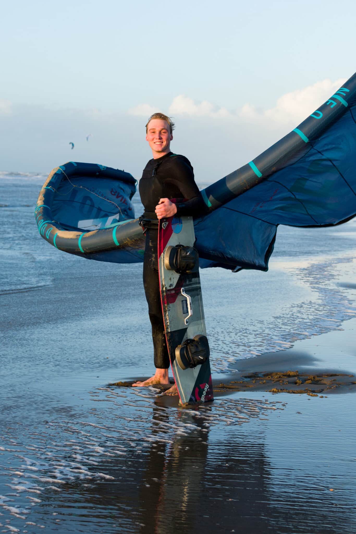 Portret van een kitesurfer die in de zee staat met zijn kite in Zandvoort.