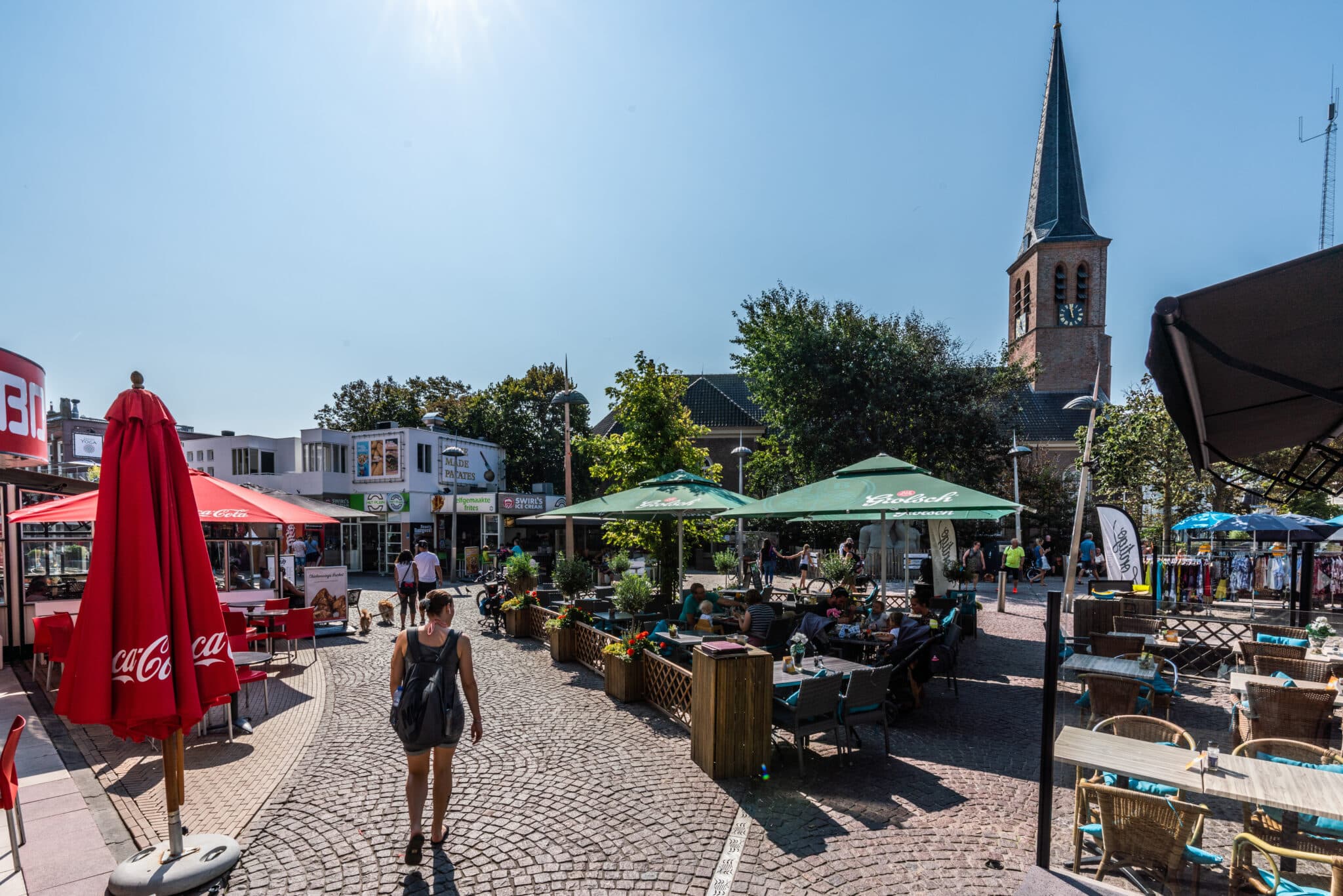 Overzicht van het Kerkplein met terrassen in de voorgrond en de kerk in de achtergrond.