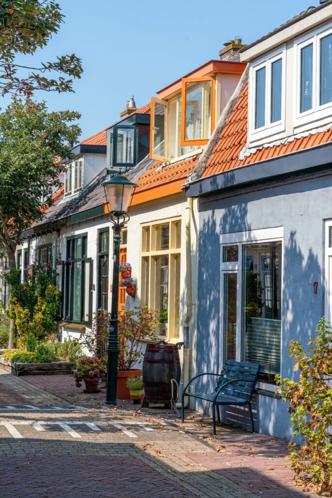 Gekleurde vissershuisjes in het centrum van Zandvoort, deel van de Sloppies, met lantaarnpaal en bankje.
