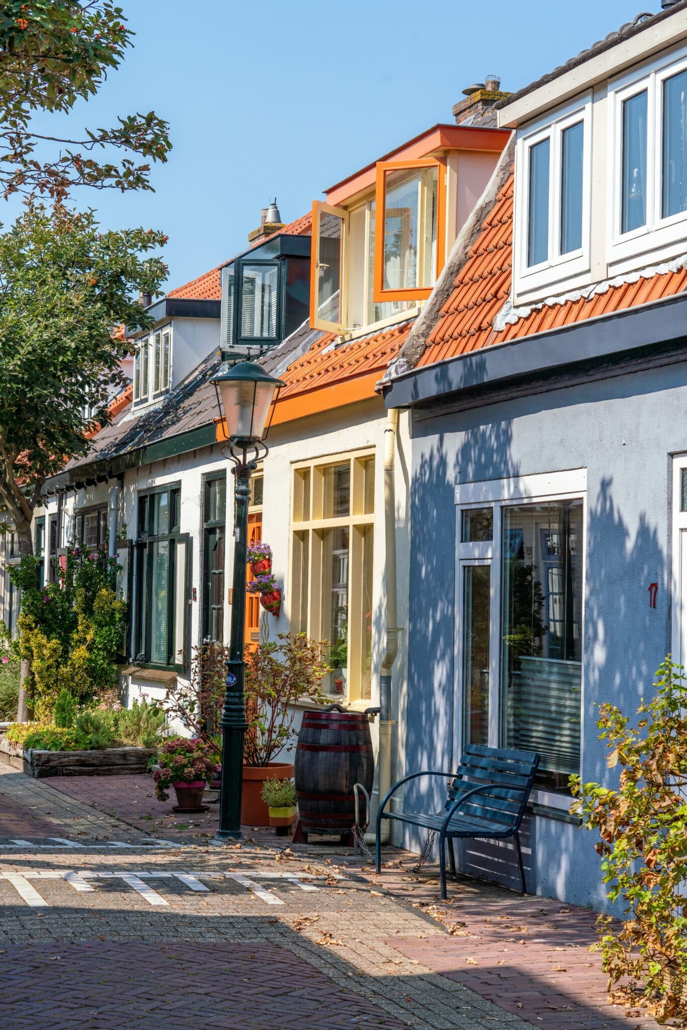 Gekleurde vissershuisjes in het centrum van Zandvoort, deel van de Sloppies, met lantaarnpaal en bankje.