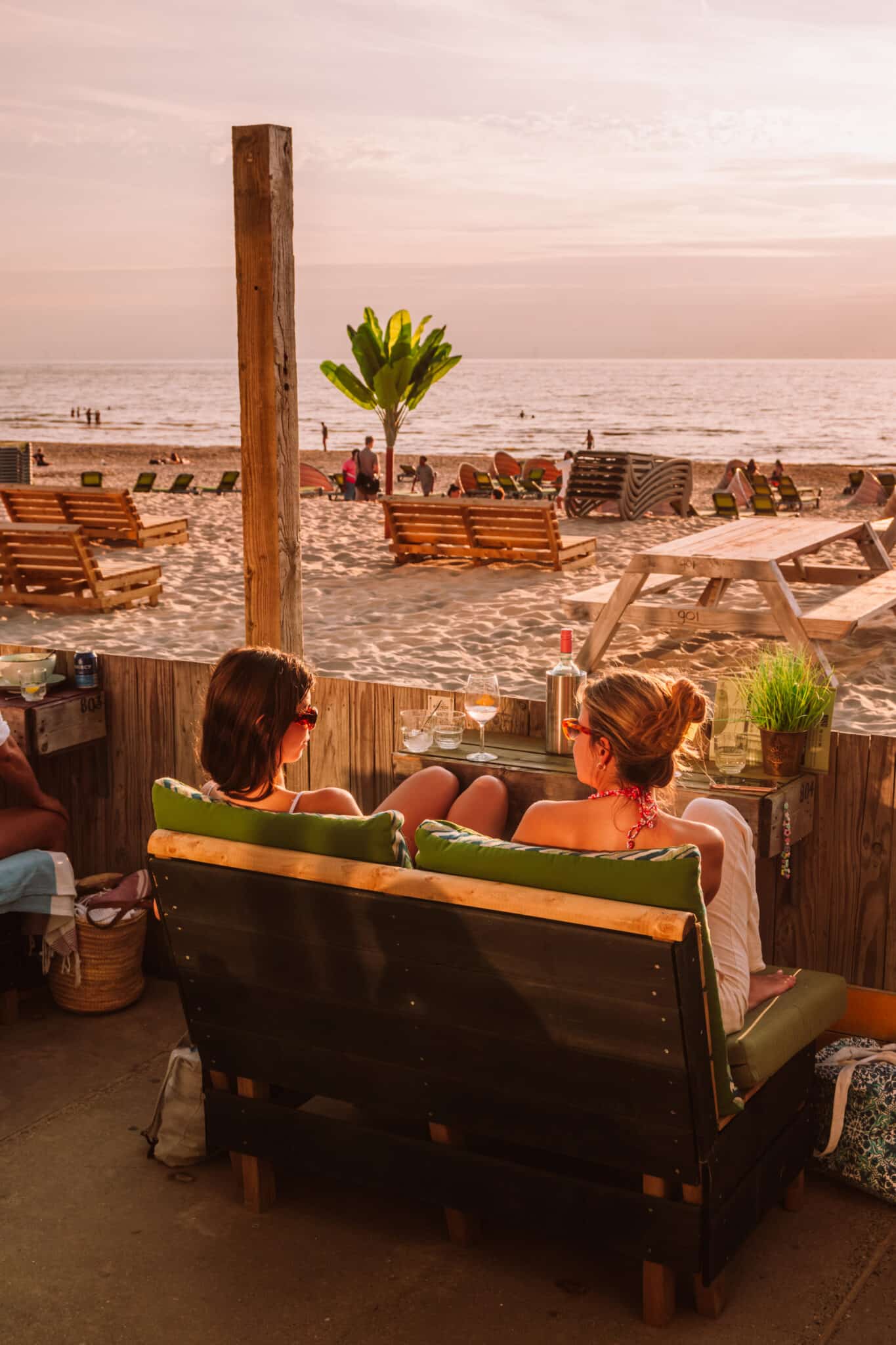 Twee vriendinnen genieten van een drankje op het strand.