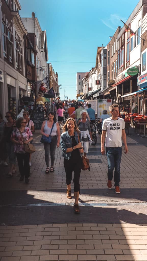 Het is druk in de Kerkstraat, waar een mensenmassa door de winkelstraat richting het centrum van Zandvoort loopt.