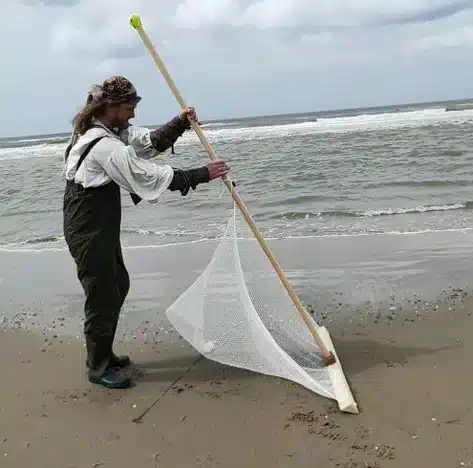 bram Molenaar, klimaat piraat in een waadpak met en garnaalvisnet voor het garnalen vissen