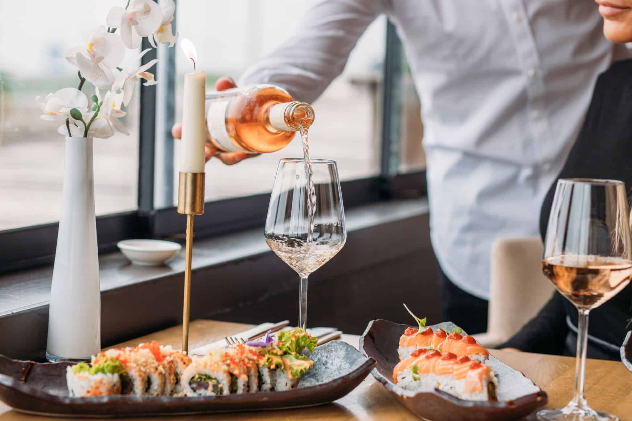 Een sushiplateau op tafel terwijl er wijn wordt ingeschonken in restaurant Zizo Lounge.