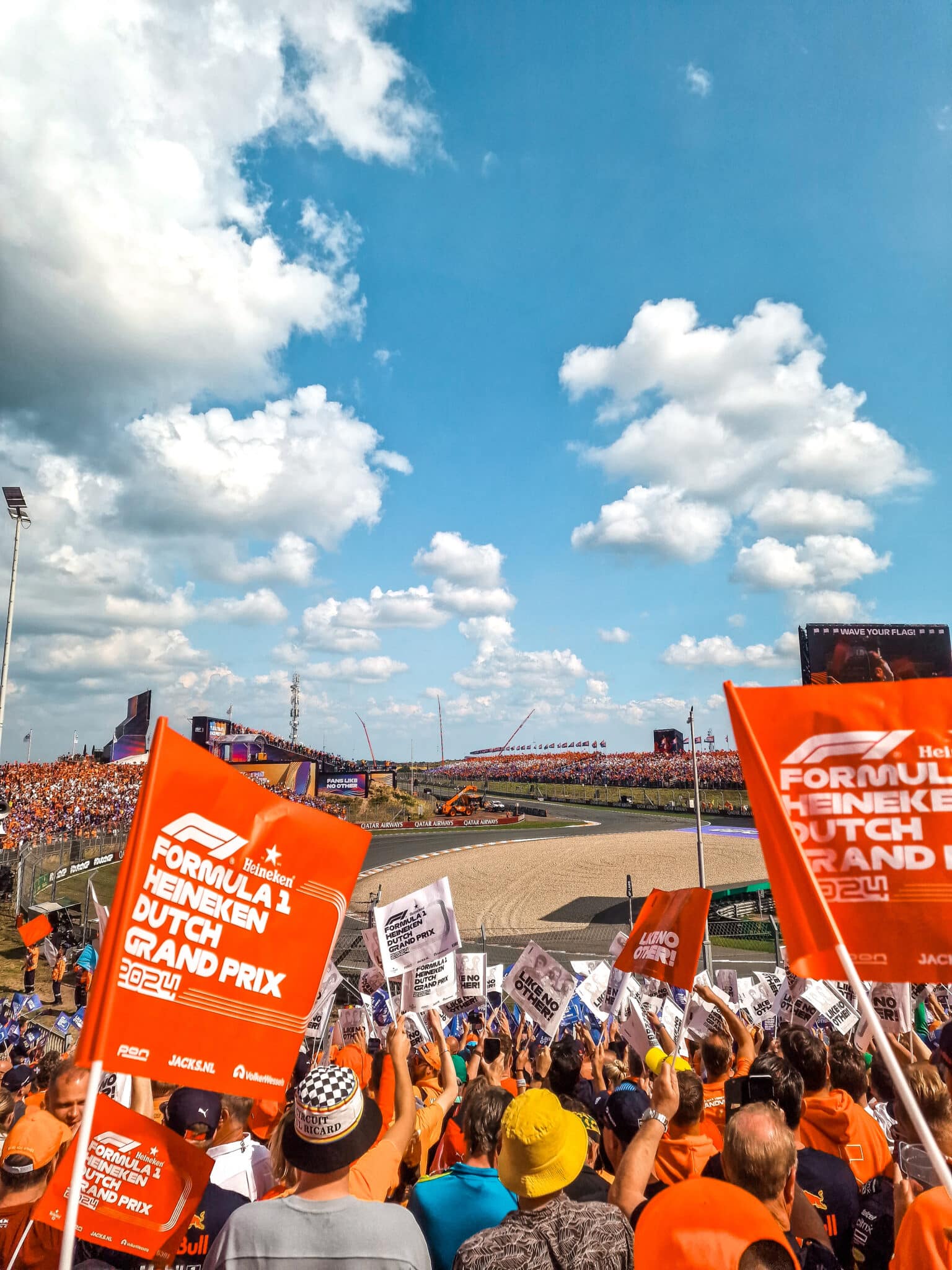 Tribune met juichende mensen en de baan van het circuit op de achtergrond tijdens de Formula 1 Heineken Dutch Grand Prix.
