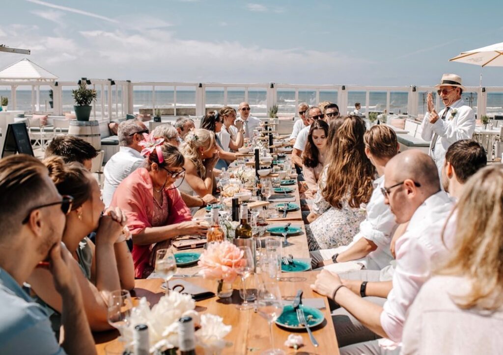 Groter trouwgezelschap aan tafel bij strandpaviljoen Meijer aan Zee