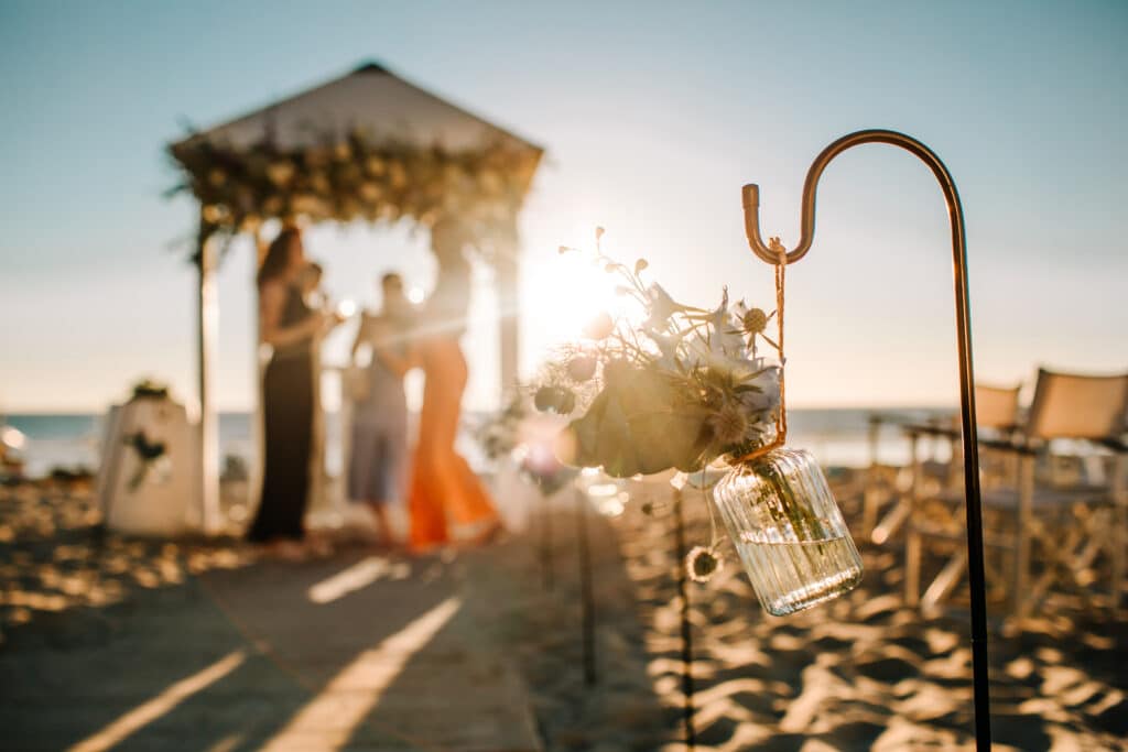 Trouwen op het strand: Stel trouwt onder een prieel op het strand bij ondergaande zon