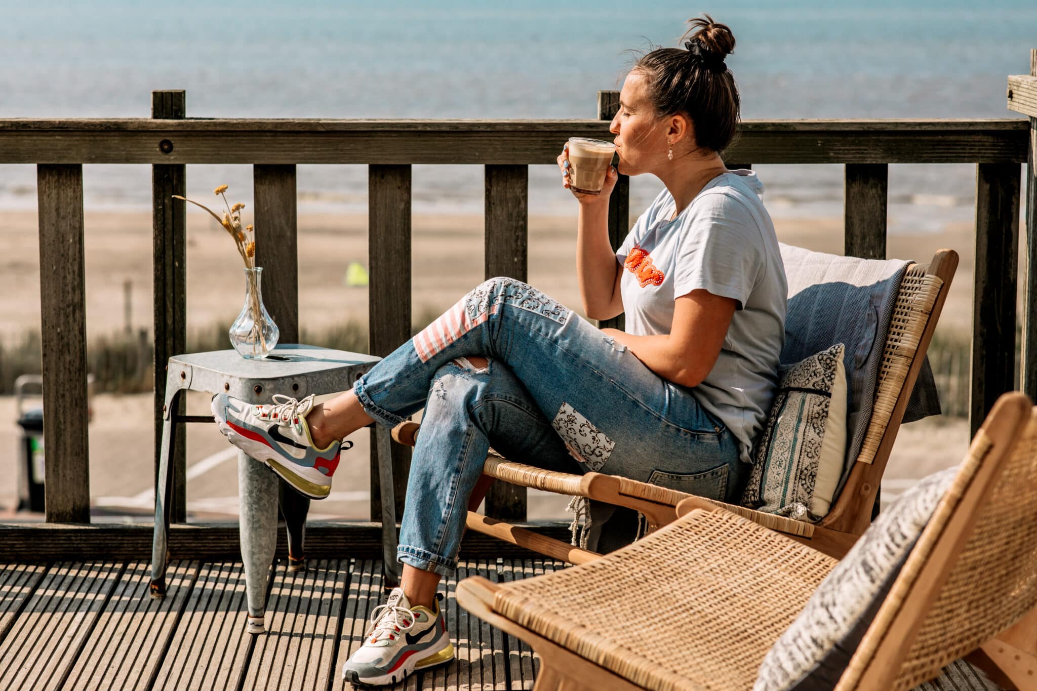 Vrouw in de zon op het terras van haar appartement bij Boulevard 5 met een kopje koffie