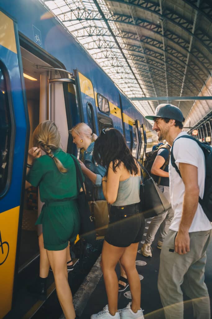 3 vrouwen en een man stappen in de trein op NS station Amsterdam Centraal