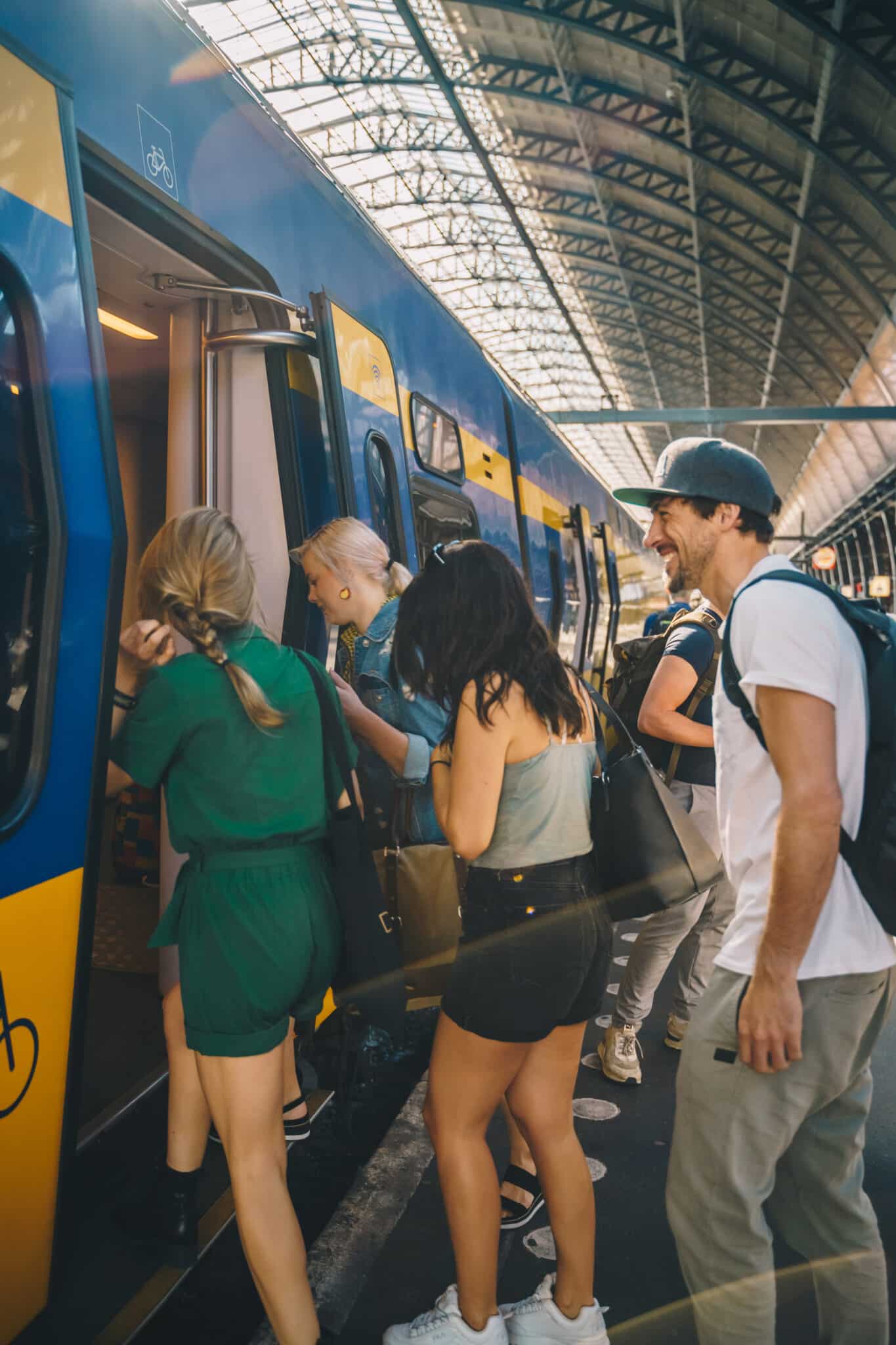 3 vrouwen en een man stappen in de trein op NS station Amsterdam Centraal