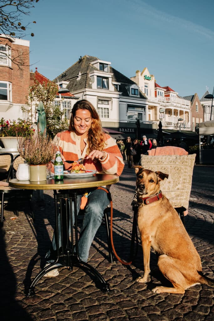 Vrouw met hond op het terras bij restaurant en hotel accommodatie Le Bar