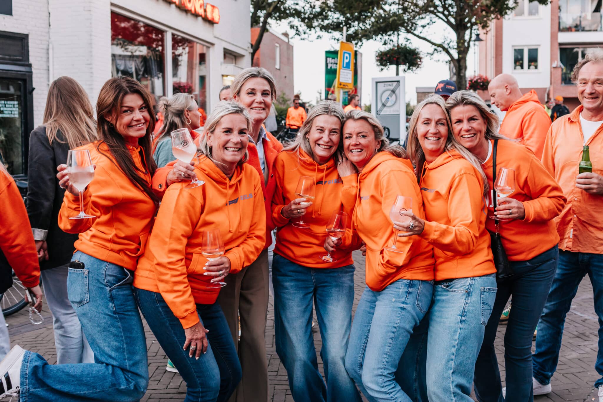 Een lachende groep vrouwen gekleed in het oranje tijdens het Zandvoort Racefestival.