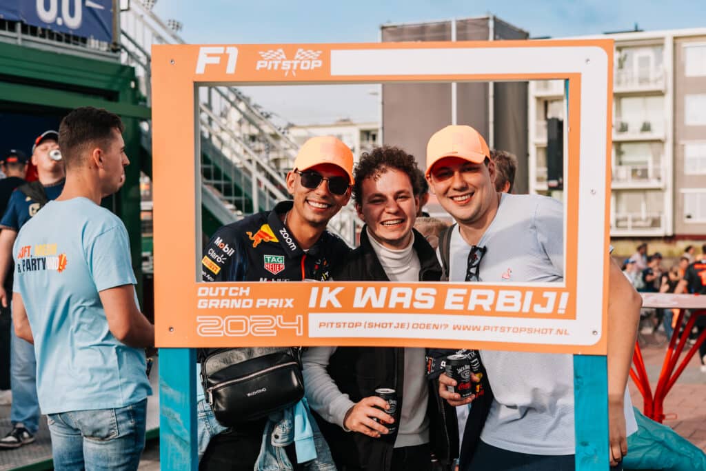 Drie blije vrienden poseren voor de foto terwijl ze een kader vasthouden tijdens de Dutch Grand Prix.