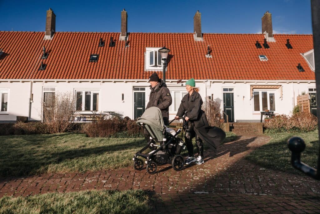 Twee personen die wandelen met een kinderwagen door de Zandvoortse sloppies