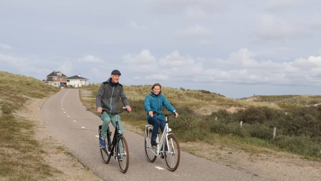 Twee mensen fietsen door de duinen