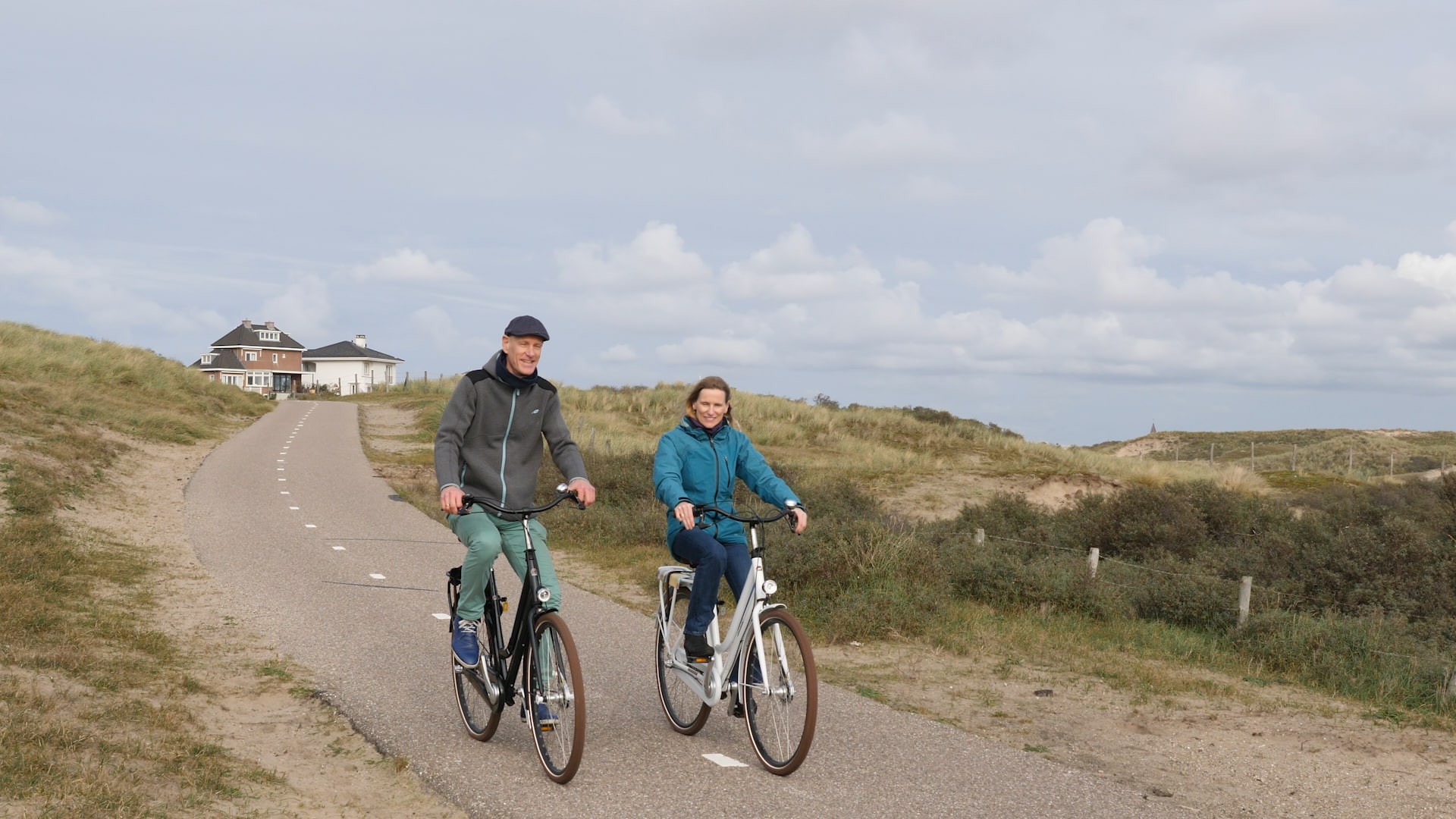 Twee mensen fietsen door de duinen