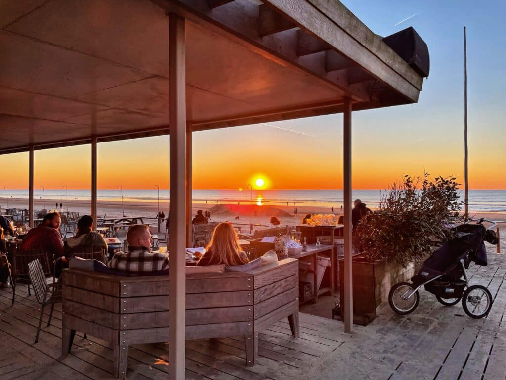 Terras van strandpaviljoen Tijn Akersloot met ondergaande zon op de achtergrond