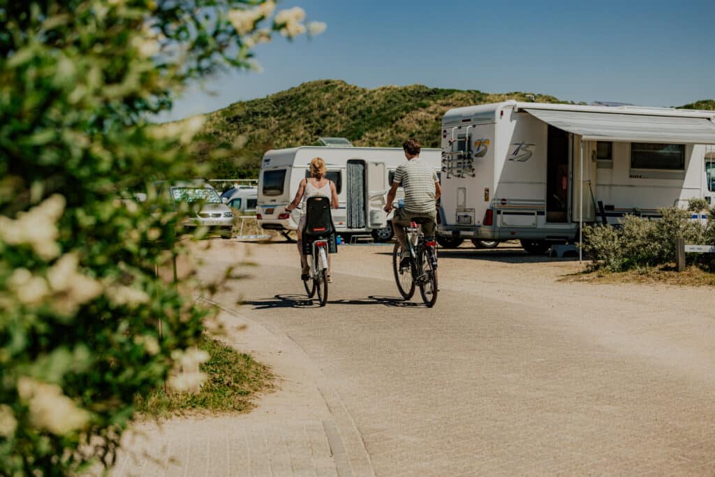 twee mensen fietsen langs caravans op camping de lakens