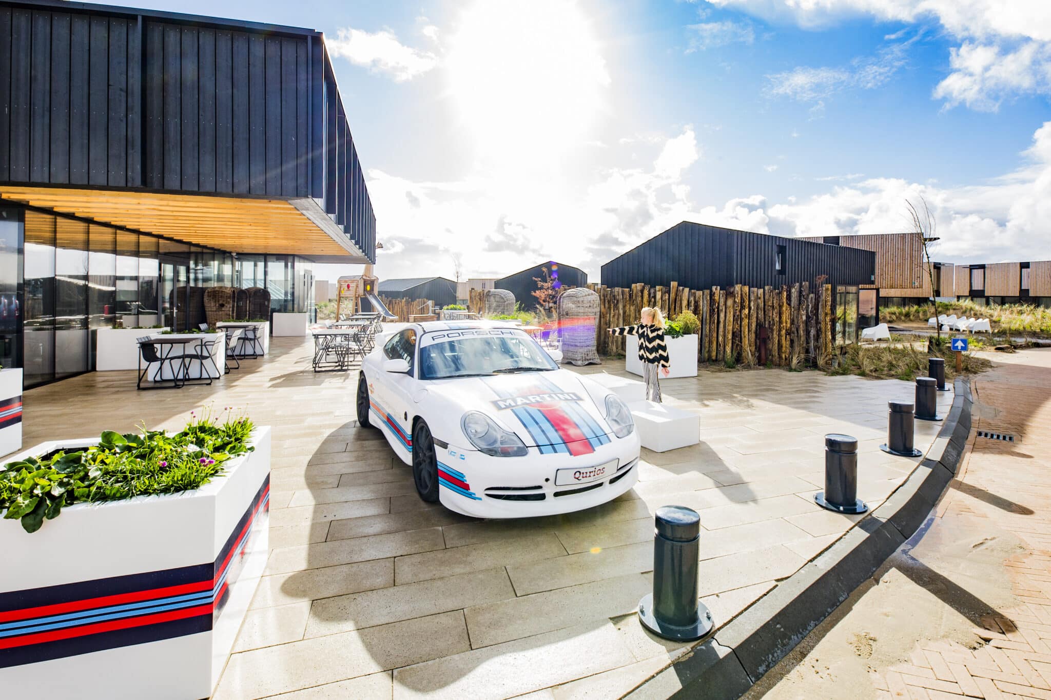 Aanzicht van het exterieur van de receptie bij Roompot Zandvoort met een raceauto met martini striping voor de deur