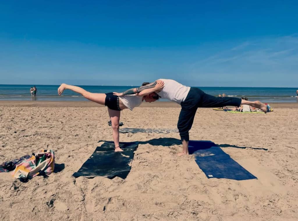 Twee mensen doen aan yoga op het strand - Yoga Shanti