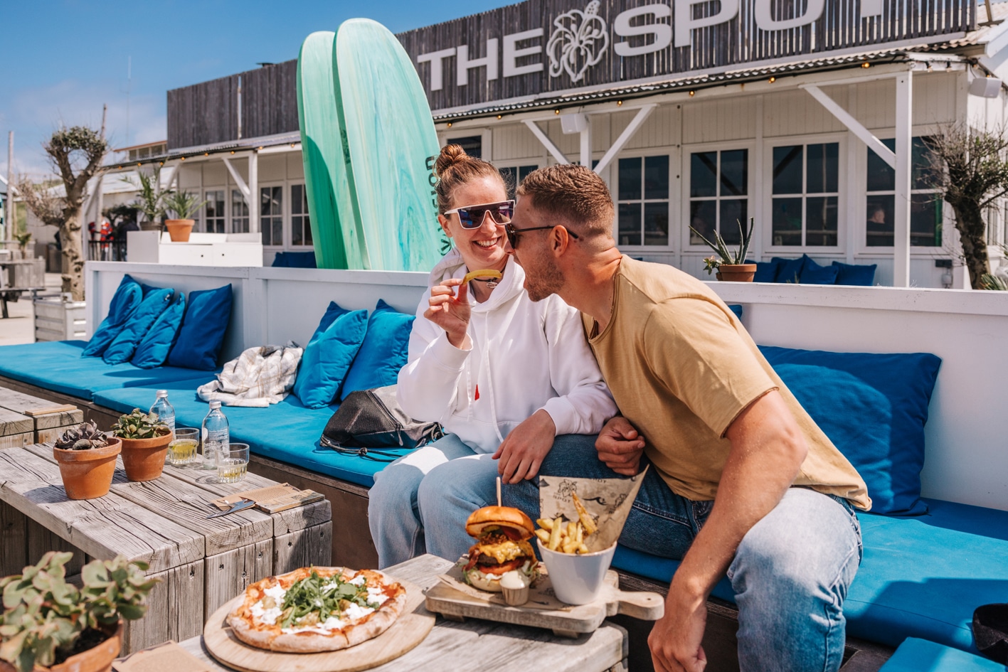 Man en vrouw hebben lunch op het terras van Watersportcentrum en strandpaviljoen The Spot