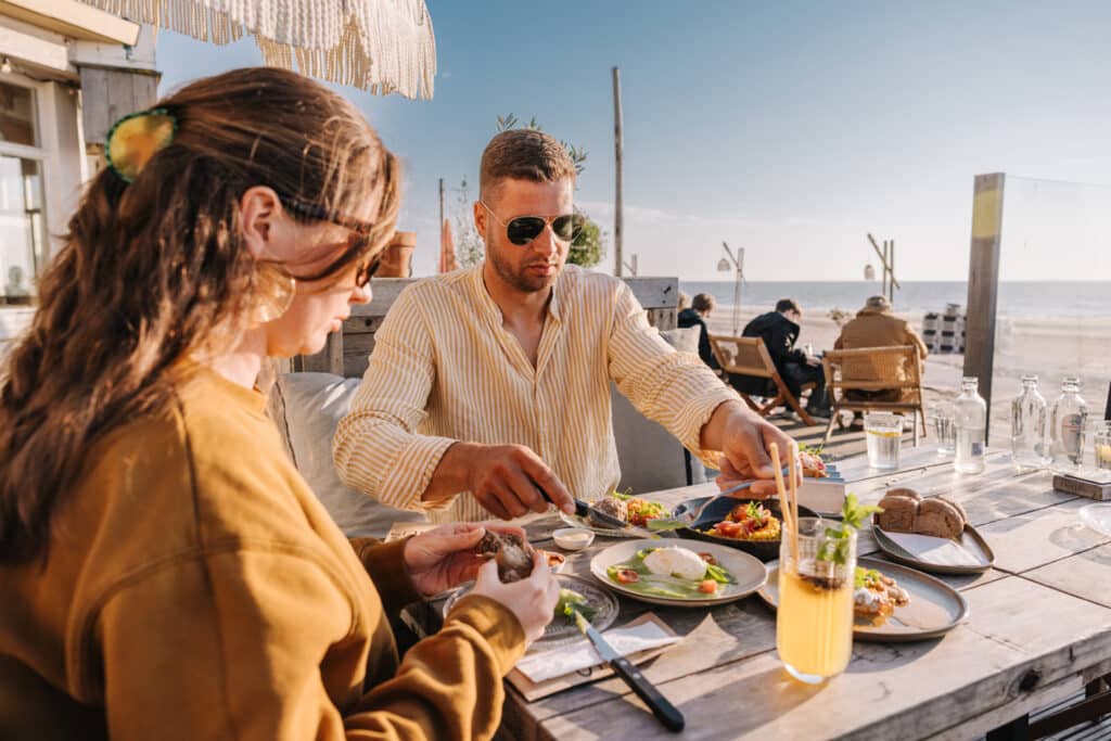 Man en vrouw dineren op het terras van Nius Beach House op het strand