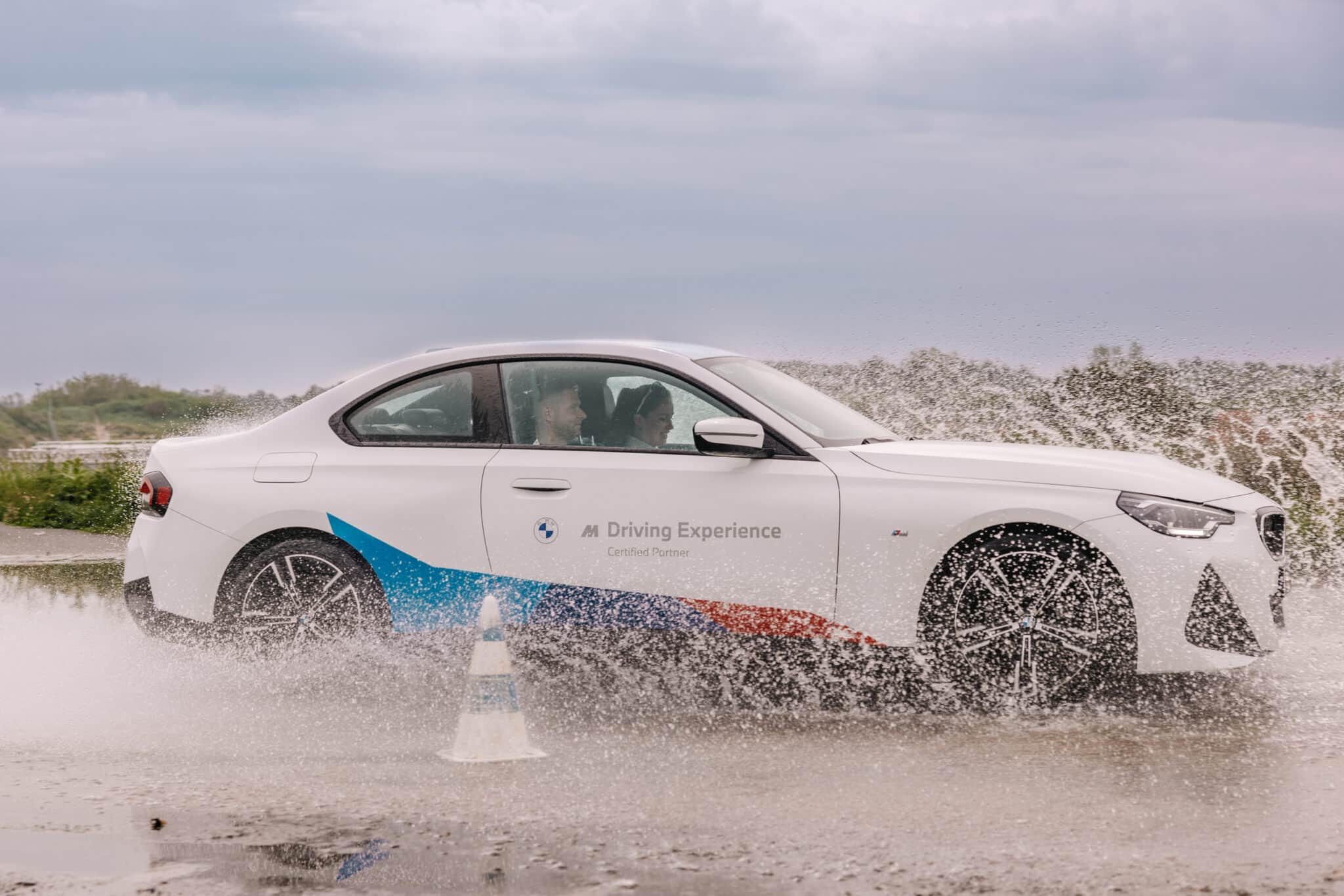 Vrouw achter het stuur van en slippende auto tijdens een cursus van BMW Driving Experience Slotemakers