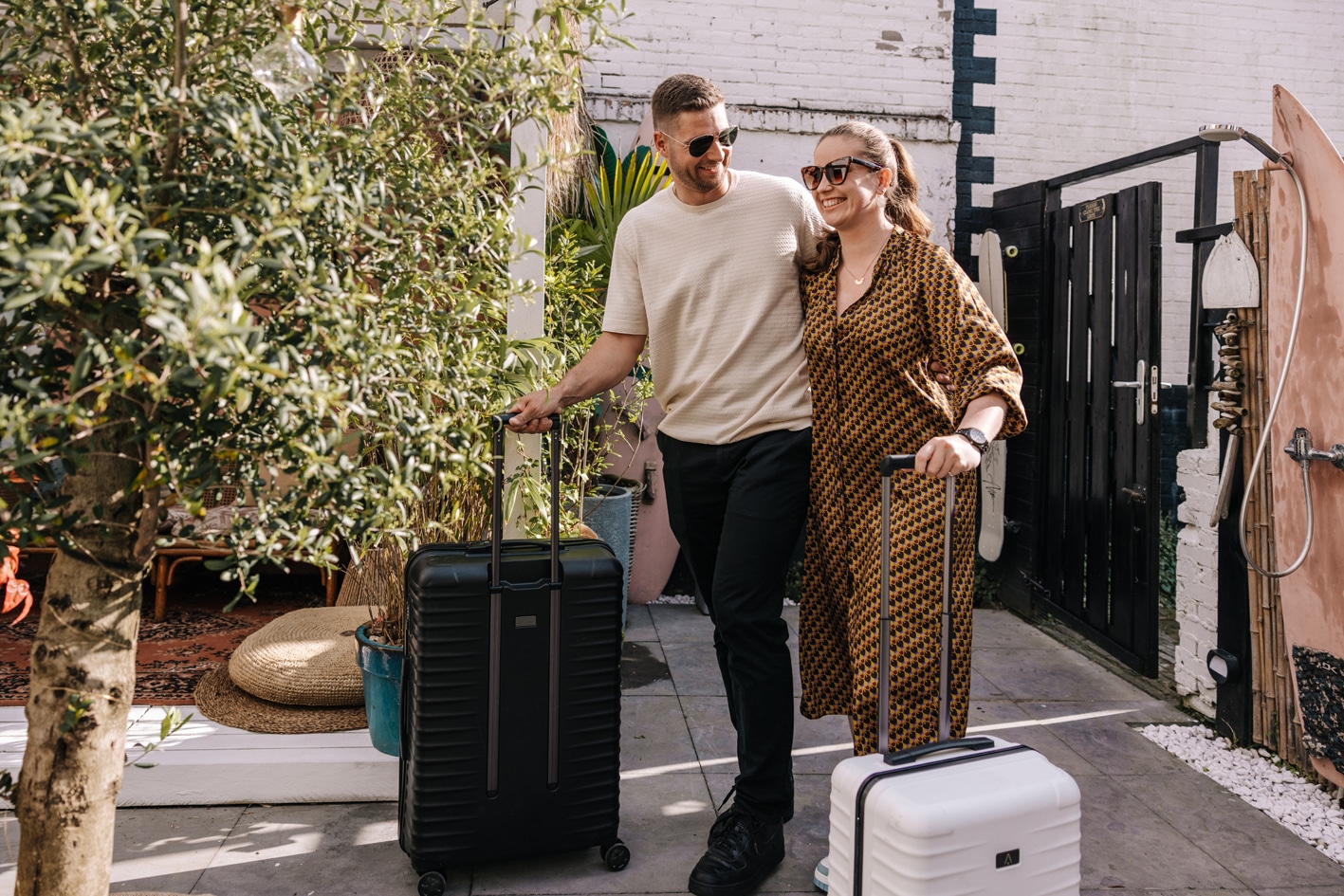 Man en vrouw lopen met koffers over het terrein van hun vakantiehuisje Tiny Paradise.
