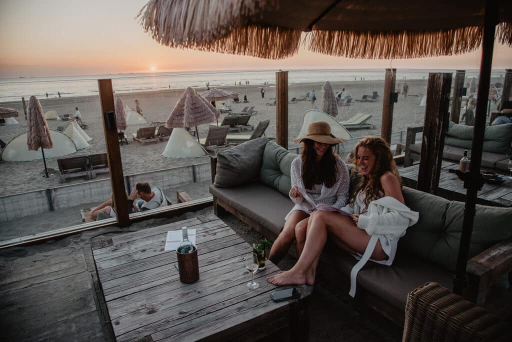 Twee jonge meiden op het terras van strandtent Far Out in Zandvoort bij ondergaande zon
