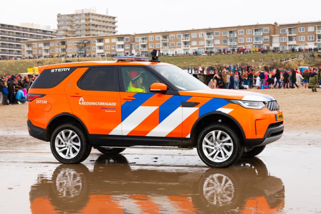 Oranje auto van de reddingsbrigade Zandvoort op het strand tijdens de nieuwjaarsduik