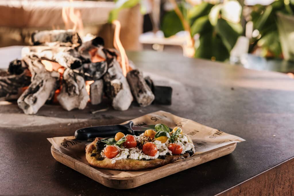 Plank met eten bij de open haard bij Nius Beachhouse