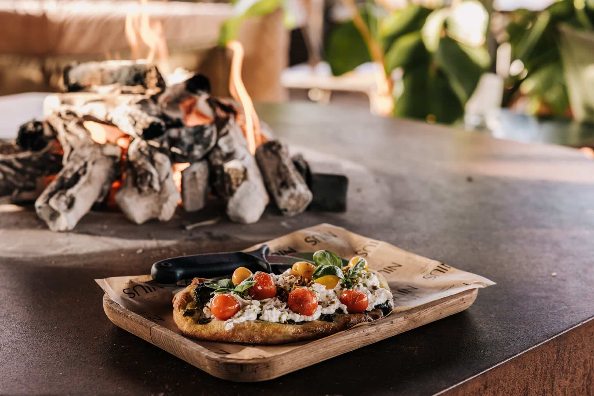 Plank met eten bij de open haard bij Nius Beachhouse
