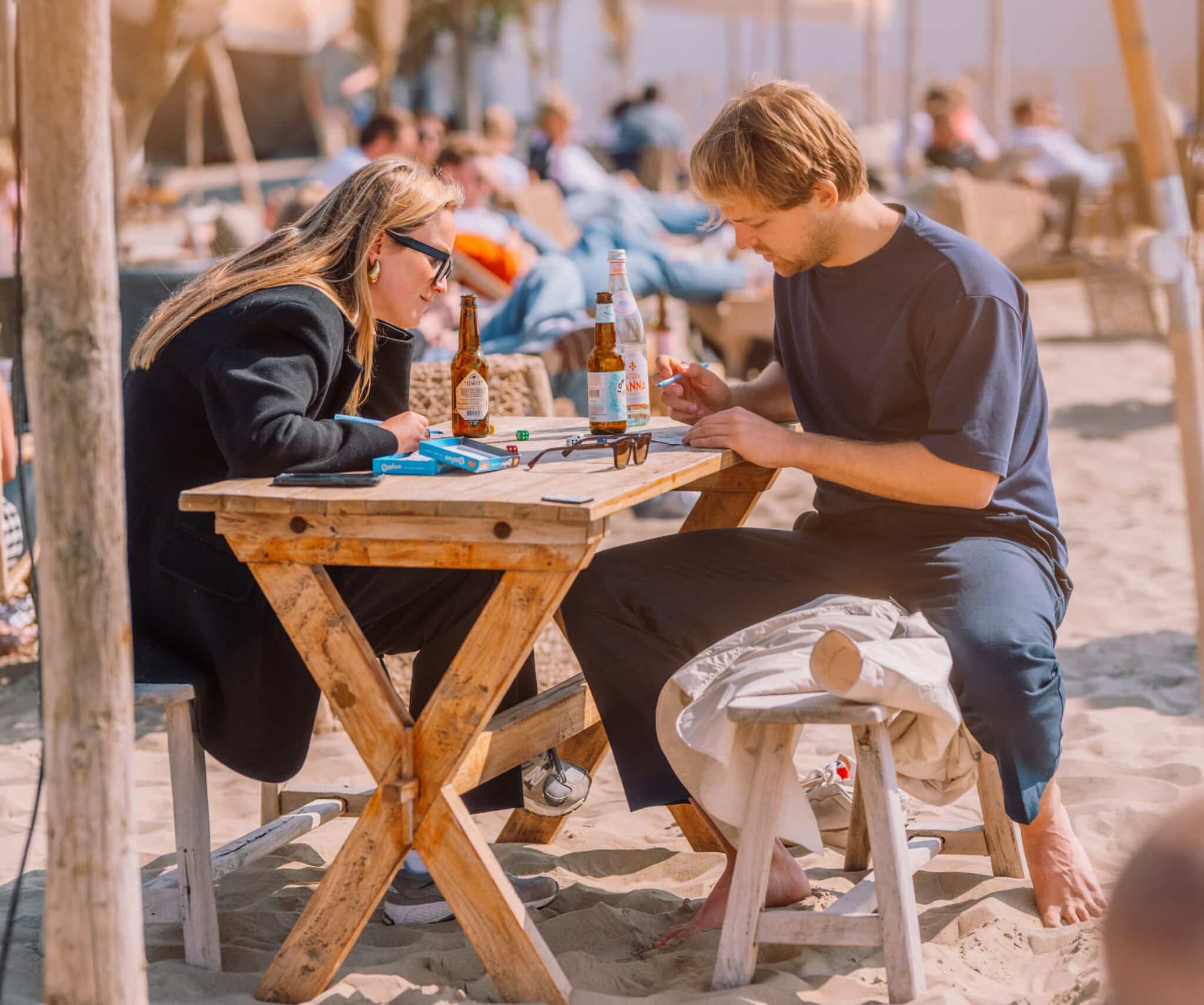 Twee personen op het strand aan een picknicktafel