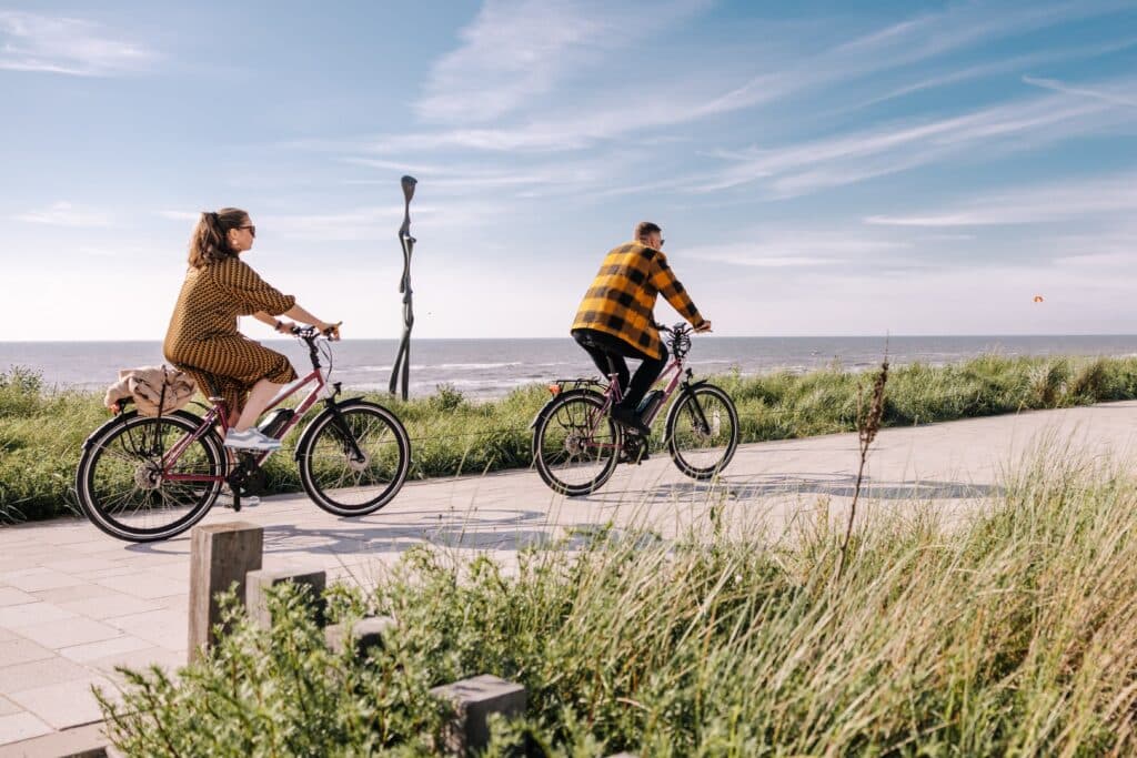 Stel fietst over de boulevard in het voorjaar langs de zee